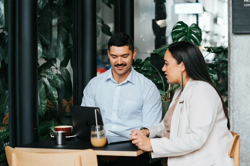Two people chatting over laptops in a café