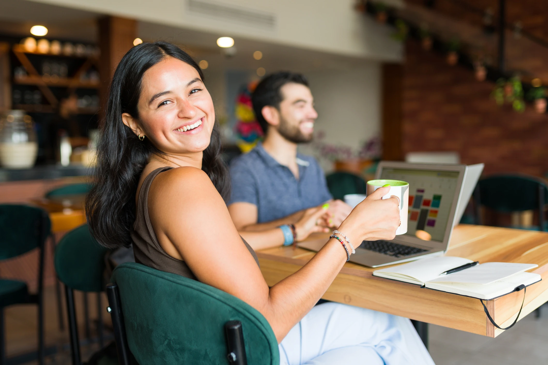 Remote worker smiling with a coffee while working from a café